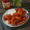 A plate of Franks RedHot Wings with a side of ranch dressing and celery.
