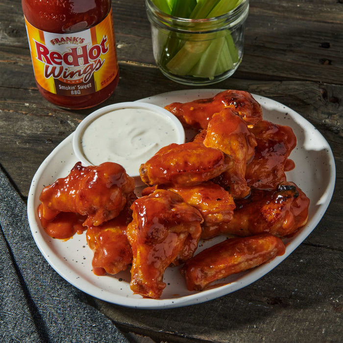 A plate of Franks RedHot Wings with a side of ranch dressing and celery.