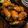 A close-up of a plate of chicken wings glazed in a sweet and savory sauce.