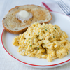 A plate of scrambled eggs with a slice of buttered toast.