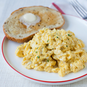 A plate of scrambled eggs with a slice of buttered toast.