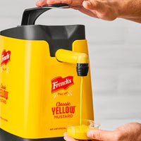 Yellow mustard dispenser with French's logo, held by a person.