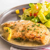 A plate of chicken breast with a lemon sauce and a side salad.