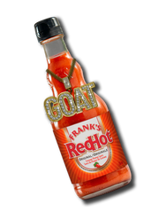 Bottle of Frank's RedHot hot sauce with 'GOAT' necklace on a white background