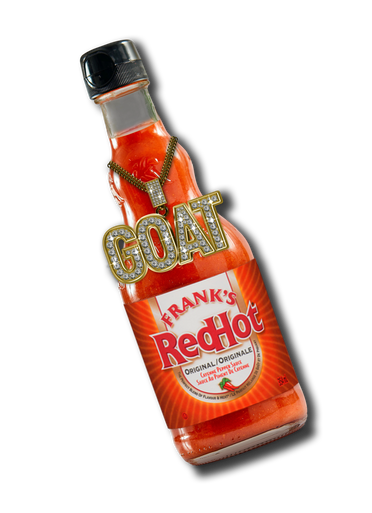 Bottle of Frank's RedHot hot sauce with 'GOAT' necklace on a white background