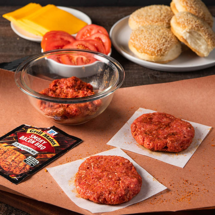 McCormick Grill Mates Smoky Bacon BBQ seasoning mix with raw burger patties and hamburger buns.
