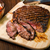 A close-up of a sliced steak on a wooden cutting board.