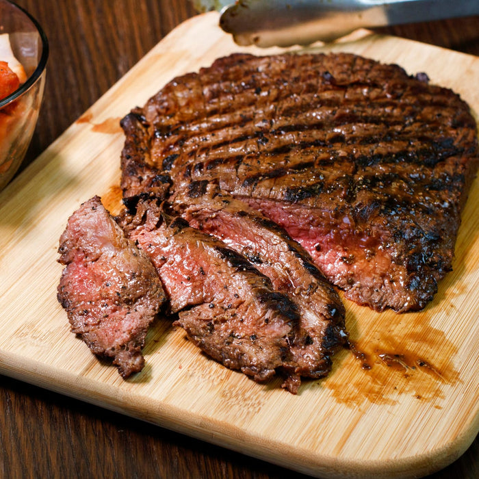 A close-up of a sliced steak on a wooden cutting board.