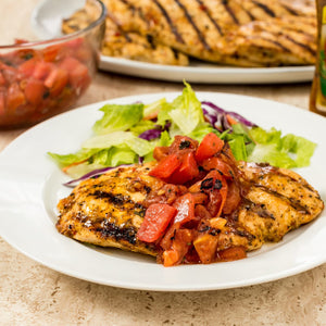 A plate of grilled chicken with tomato salsa and a side salad.