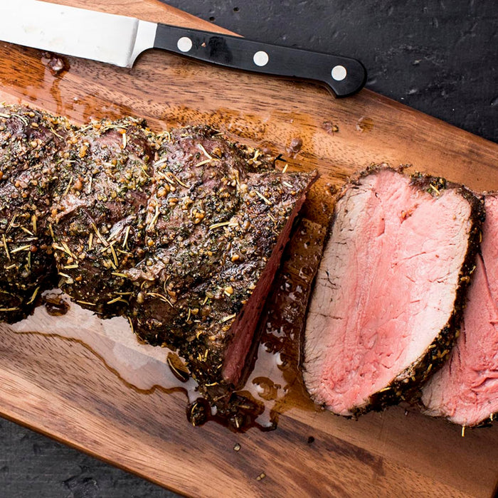 A close-up of a sliced beef tenderloin on a wooden cutting board.