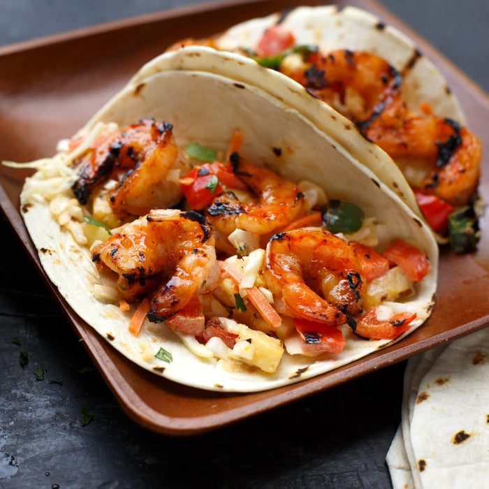 A close-up of a shrimp taco with grilled shrimp, cabbage, and other vegetables.