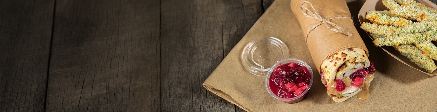 Wrap with berries and a container of jelly on a wooden surface