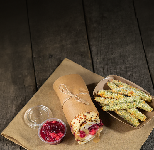 Wrap with berries, a container of red sauce on a wooden surface