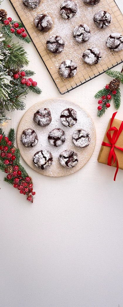 Chocolate cookies on a wooden board with Christmas decorations on a white surface