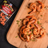 A wooden cutting board with a pile of grilled shrimp skewers and a McCormick Grill Mates Honey Sriracha Marinade Mix packet.