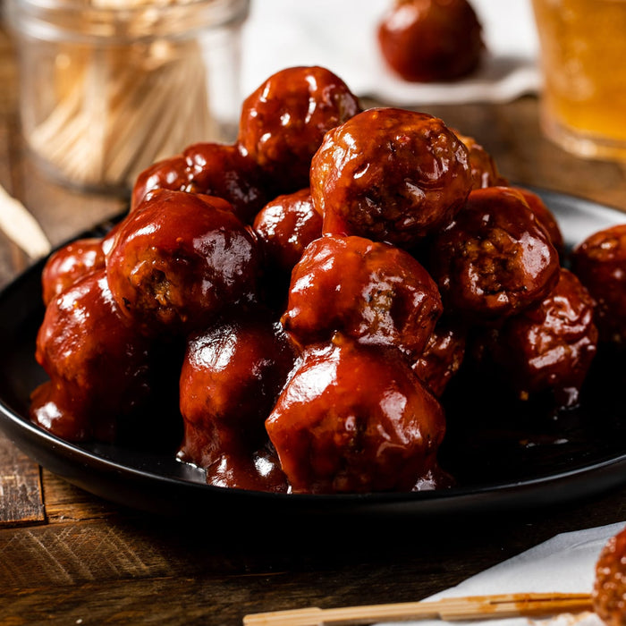 A close-up of a plate of meatballs covered in a sweet and tangy sauce.