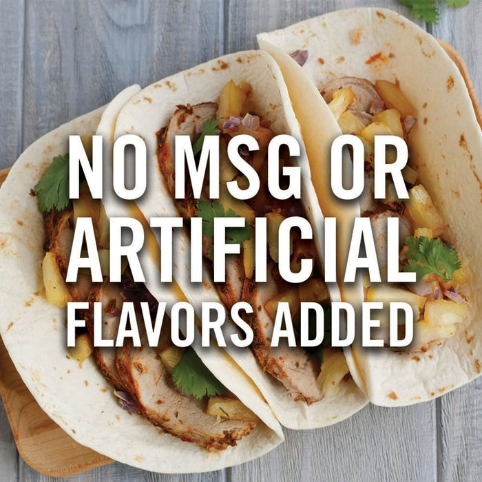 Three tacos with pork, pineapple, and red onion are on a wooden surface with the text No MSG or Artificial Flavors Added.