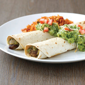 Two beef and bean burritos with guacamole and rice on a white plate.