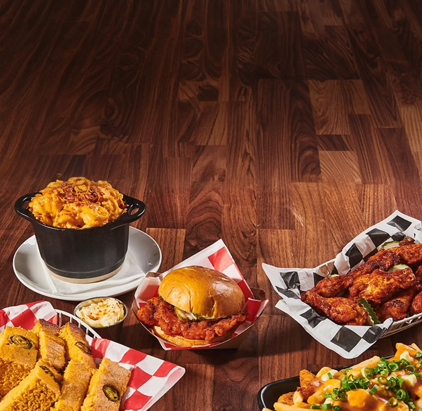 Assorted food items including a burger, fries, and macaroni and cheese on a wooden table.