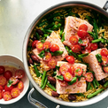Salmon dish with orzo, green beans, cherry tomatoes, and olives in a pan.