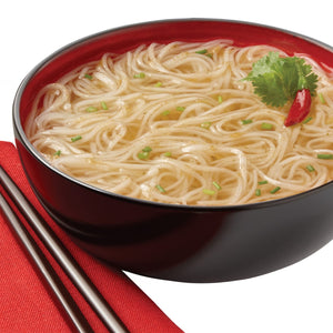 A bowl of noodles with broth and green onions, garnished with a red pepper and cilantro.