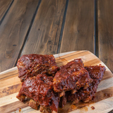 Braised ribs on a wooden cutting board with a rustic wooden background