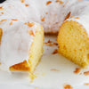A close-up of a coconut cake with white frosting and coconut flakes.