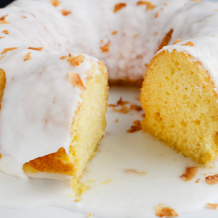 A close-up of a coconut cake with white frosting and coconut flakes.