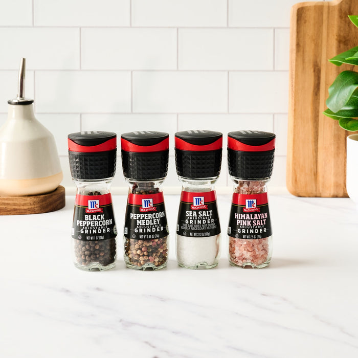 Four McCormick spice grinders, black peppercorn, peppercorn medley, sea salt, and Himalayan pink salt.