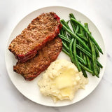 Plate of meatloaf, mashed potatoes, and green beans on a white plate.