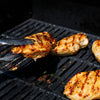 Chicken breasts seasoned with Mccormick Grill Mates Chipotle &amp; Roasted Garlic Seasoning are being grilled, with one piece held by tongs over the hot grates.