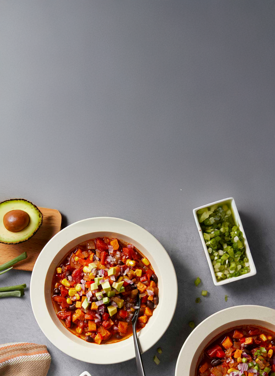 Two bowls of colorful salad with a small dish of green dressing