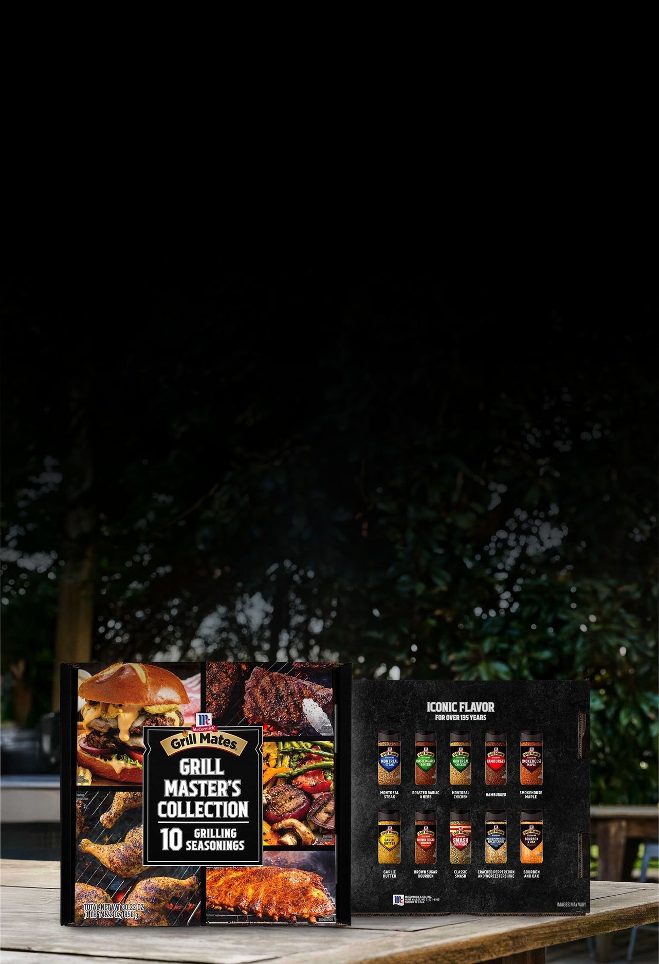 Grill Master's Collection seasoning set on a wooden table with a blurred outdoor background.