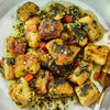 A plate of gnocchi with pesto sauce.