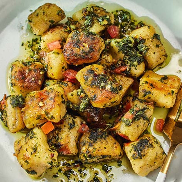 A plate of gnocchi with pesto sauce.