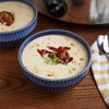 A bowl of creamy soup topped with bacon and green onions.