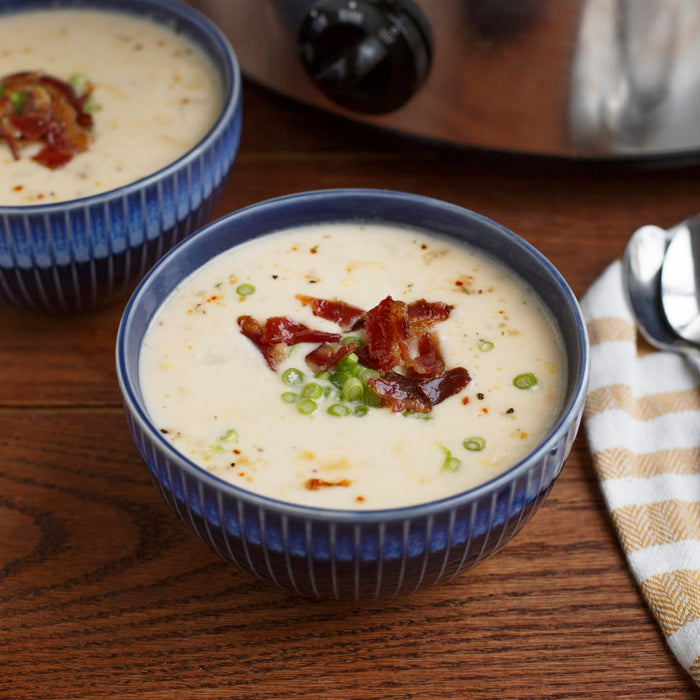 A bowl of creamy soup topped with bacon and green onions.