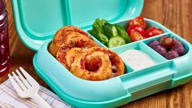 Teal bento box with pizza rolls, vegetables, and a fork on a wooden surface