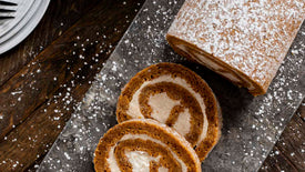 Sliced pumpkin roll on a dark surface with powdered sugar