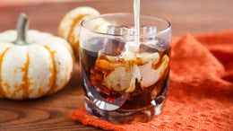 Glass of iced coffee with pumpkins on a wooden surface