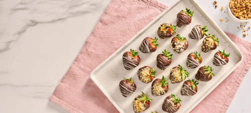 Tray of chocolate-dipped strawberries on a pink cloth with a marble background
