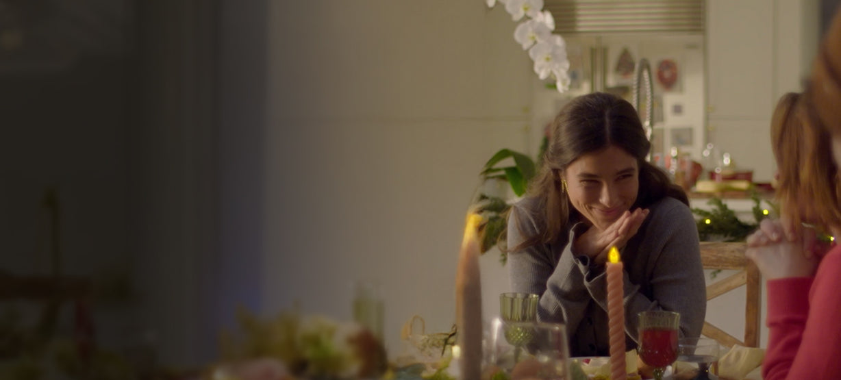 person smiling to guests at a holiday dinner table