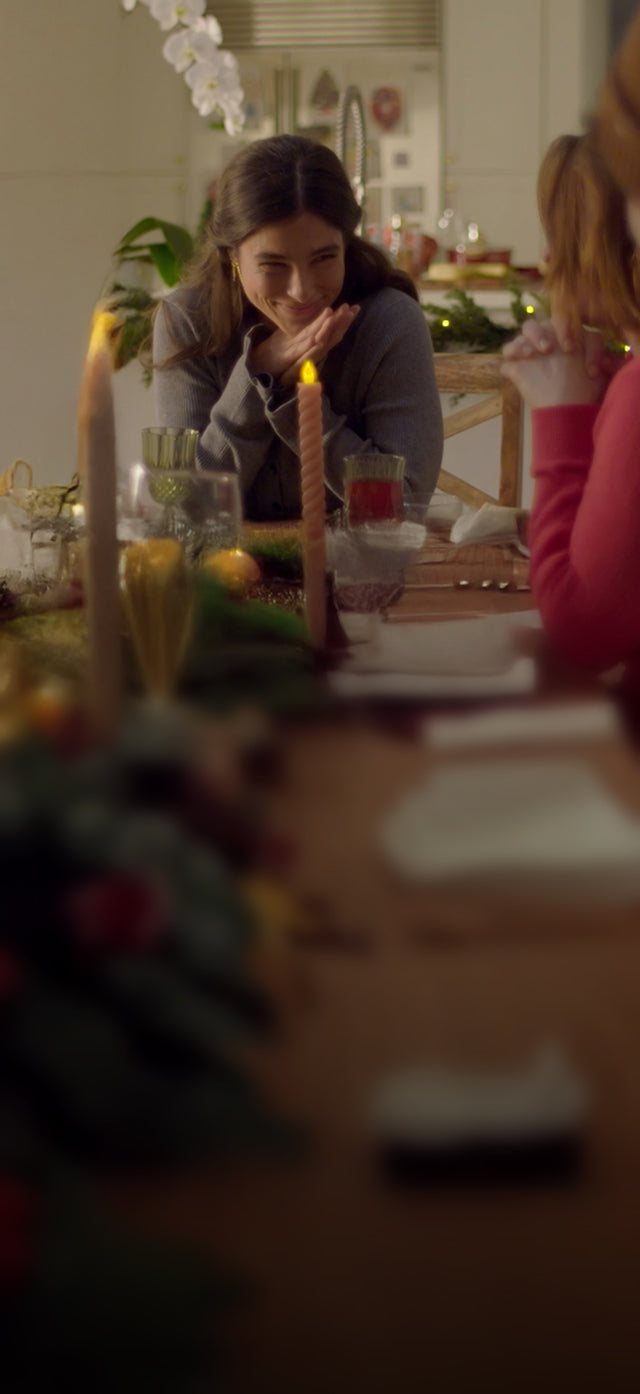 person smiling to guests at a holiday dinner table
