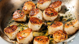 Seared scallops with herbs in a pan