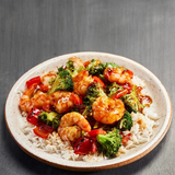 Plated dish of shrimp and broccoli over rice on a gray background