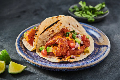 Tacos with meat, vegetables, and salsa on a blue plate with a dark background