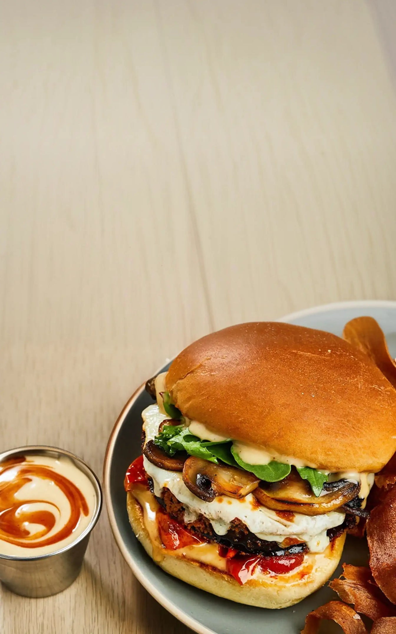 Delicious burger with various toppings on a plate against a neutral background