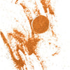 A small bowl of spices sits on a white surface with a trail of spices leading away from it.
