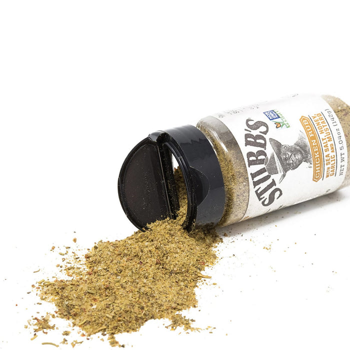 A jar of Stubbs Chicken Rub seasoning is tipped over, spilling the spice onto a white surface.