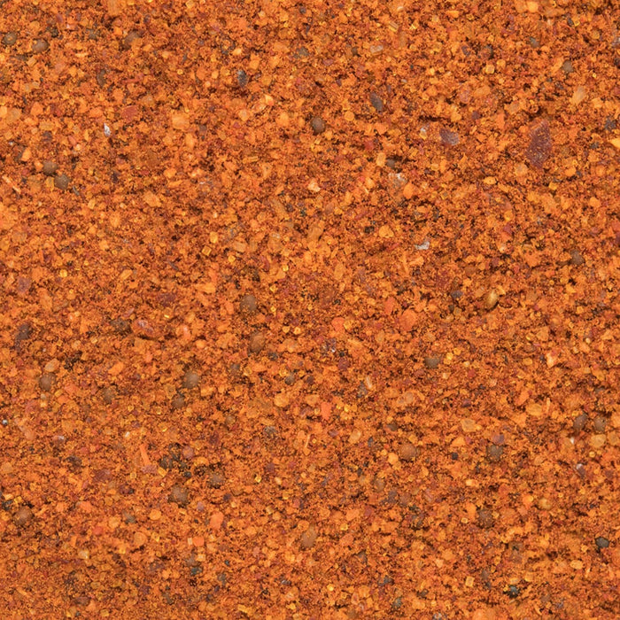 A close-up of a mixture of spices, including paprika, chili flakes, and peppercorns.